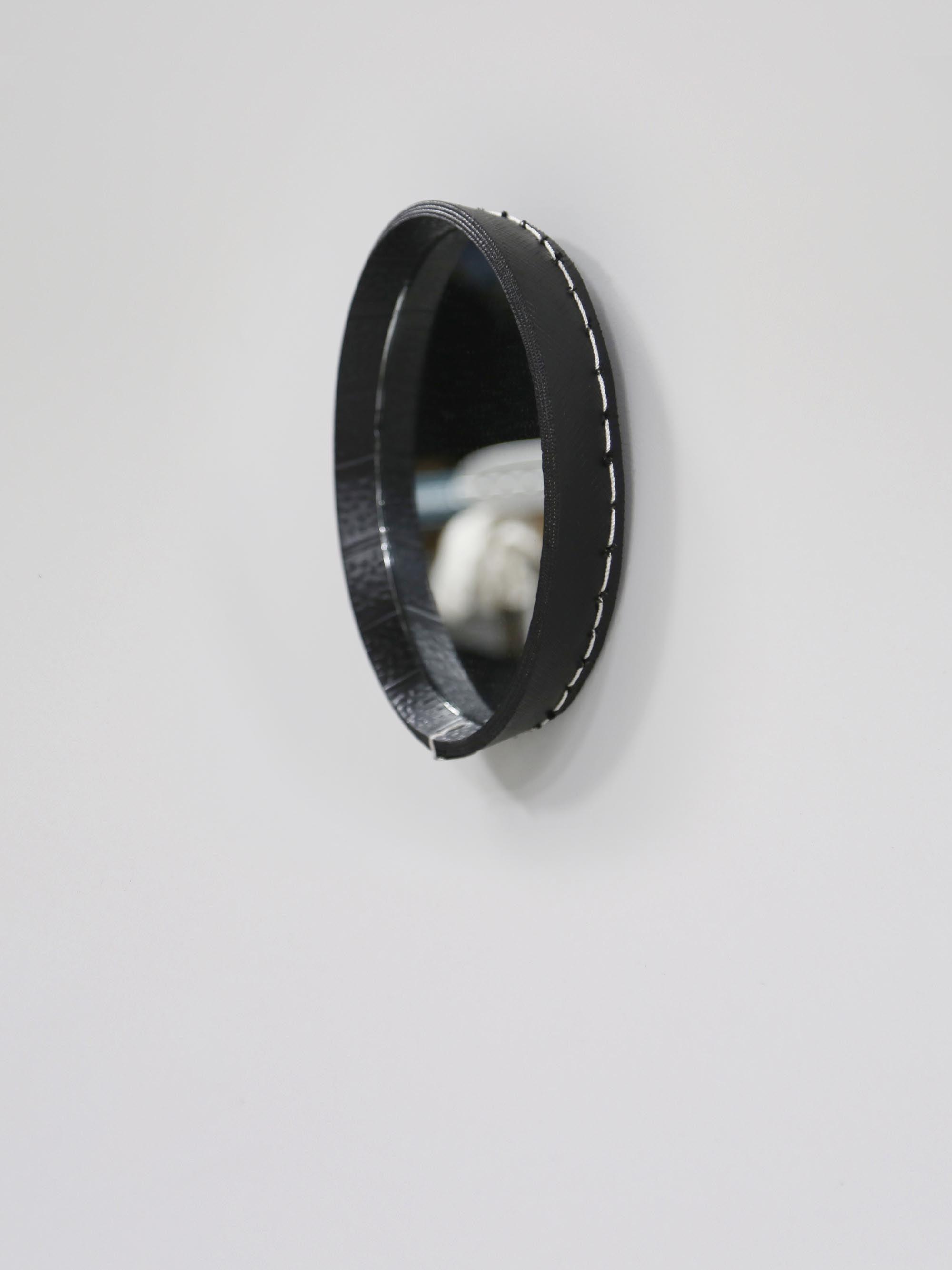 הצד של מראה עגולה גדולה תלויה על קיר אפור