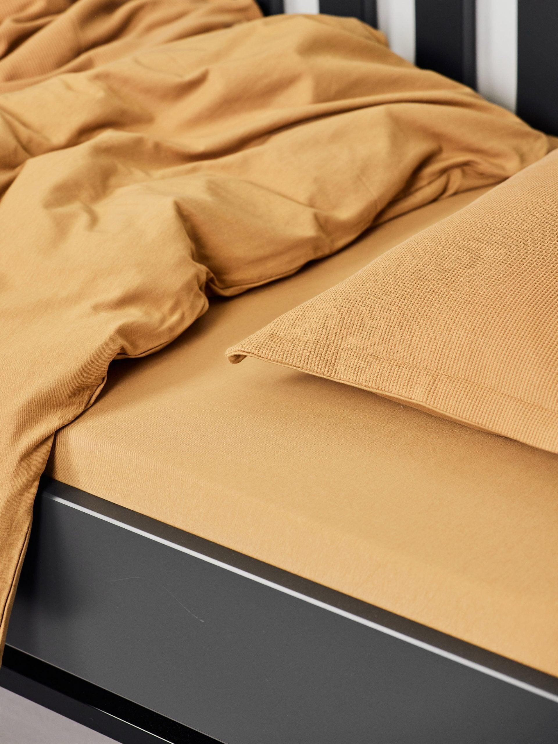 עריסת תינוק שחורה עם מצעים הכוללים סדין לתינוק, שמיכת פוך ולתינוק וכרית עם ציפית לכרית תינוק