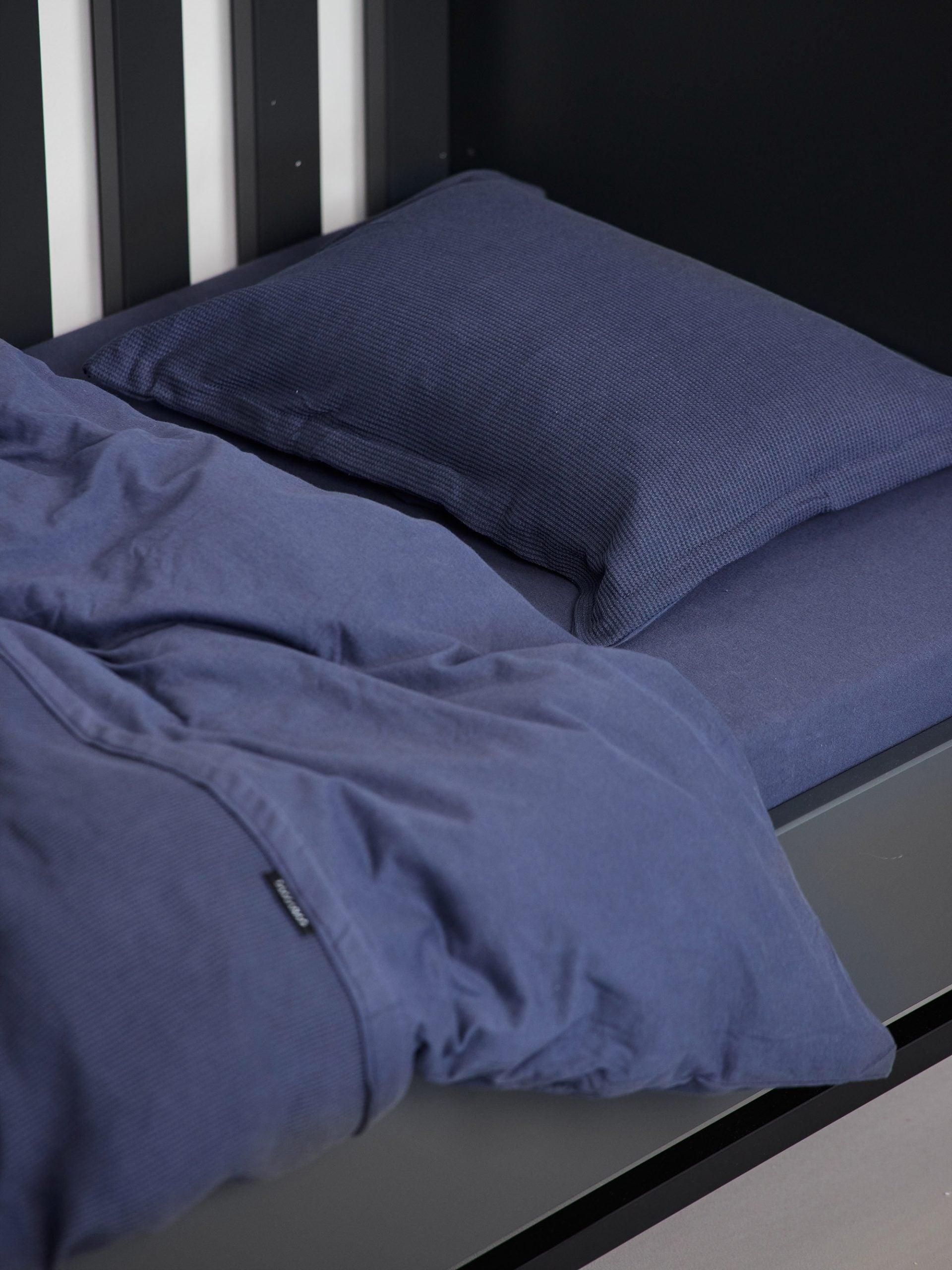 עריסת תינוק שחורה עם מצעים הכוללים סדין לתינוק, שמיכת פוך ולתינוק וכרית עם ציפית לכרית תינוק בצבע כחול