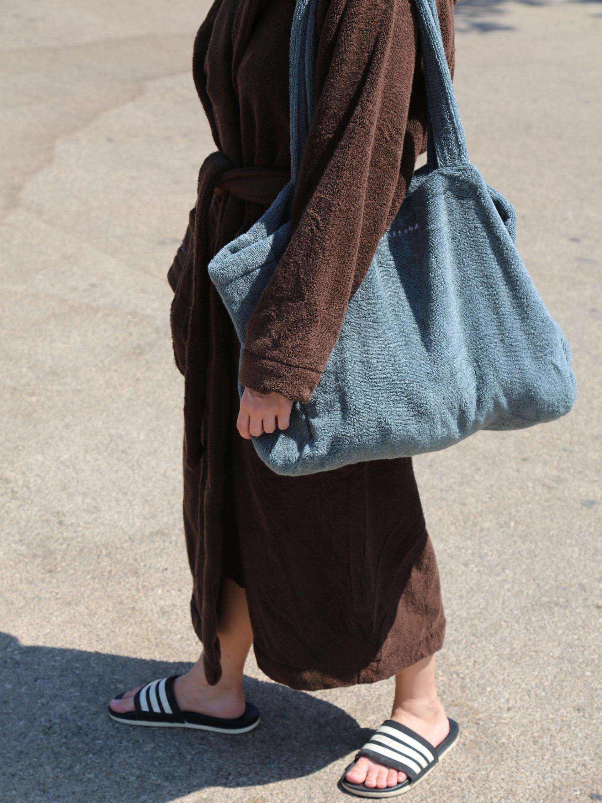 אישה לובשת חלוק ועונדת תיק לים