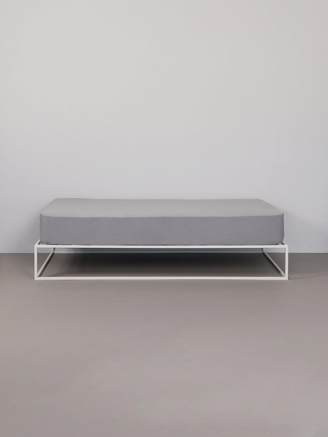 סדין ג'רסי טריקו בצבע אפור על מיטת ברזל לבנה