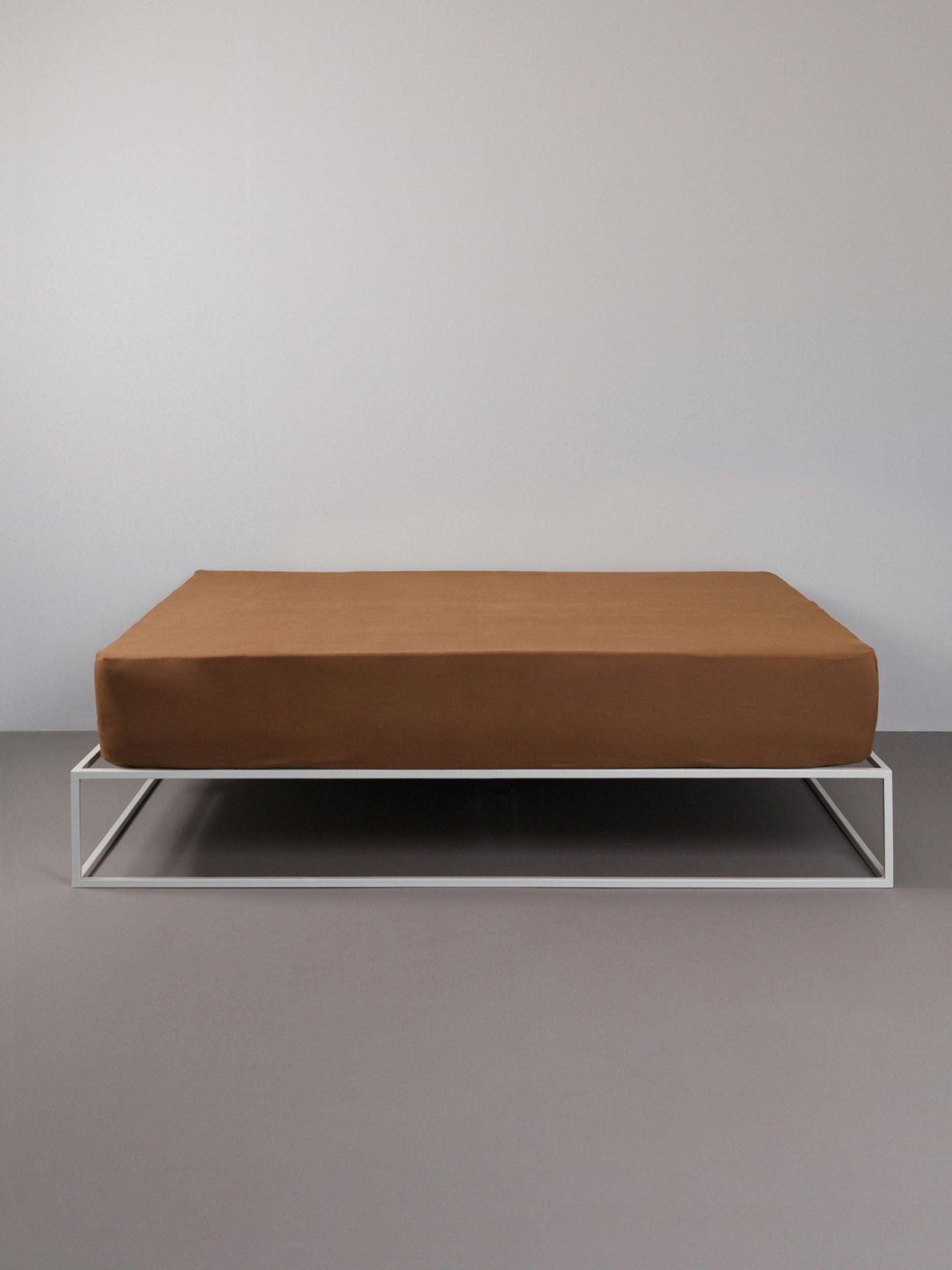 סדין ג'רסי טריקו בצבע טופי על מיטת ברזל לבנה