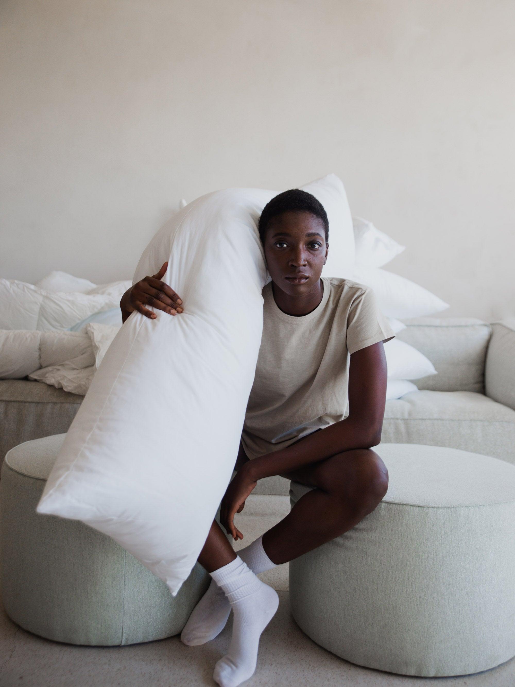 אישה מחזיקה כרית ארוכה ומפנקת