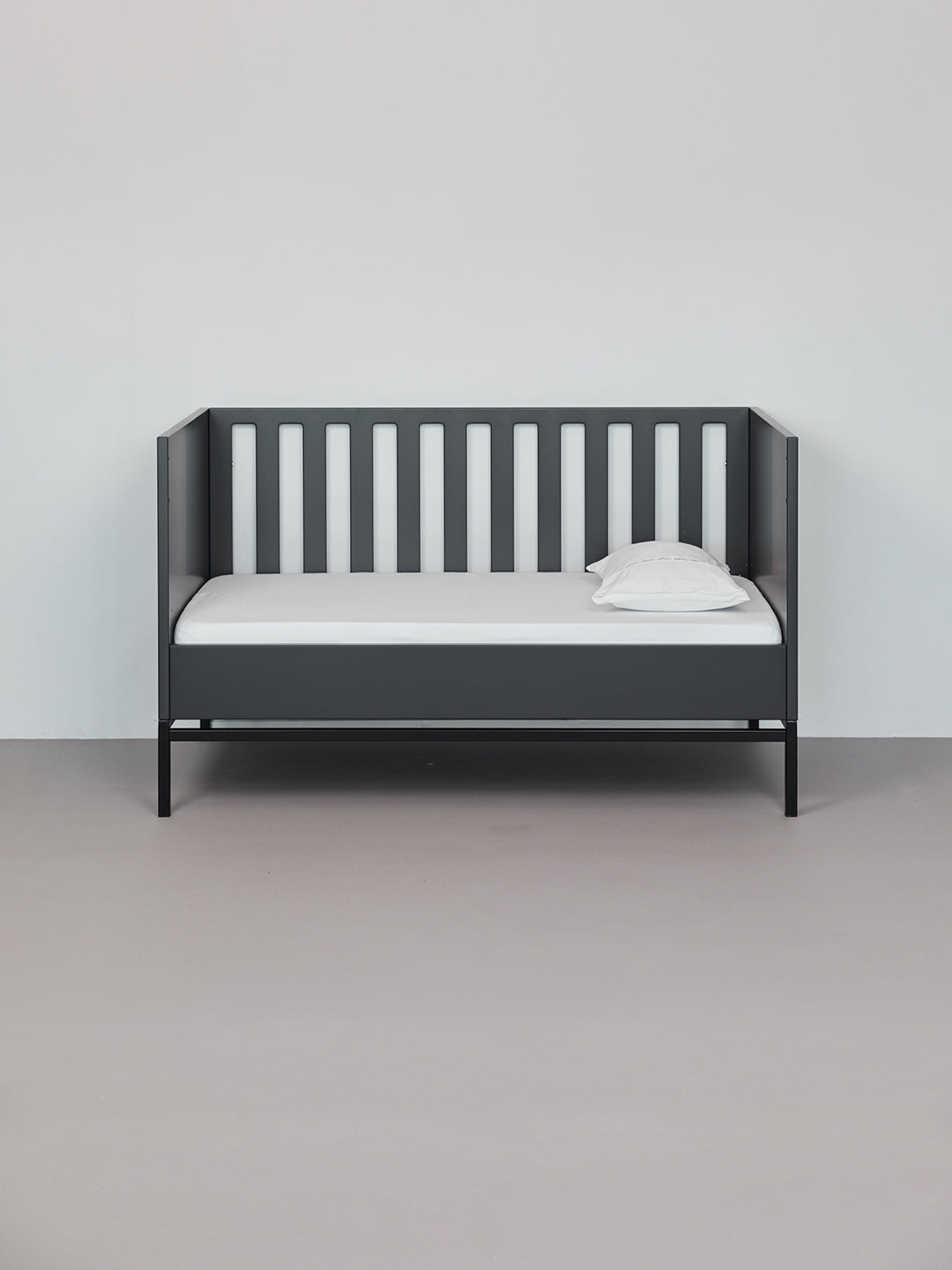 כרית עם ציפית לכרית קטנה  בצבע לבן בתוך מיטת תינוק שחורה