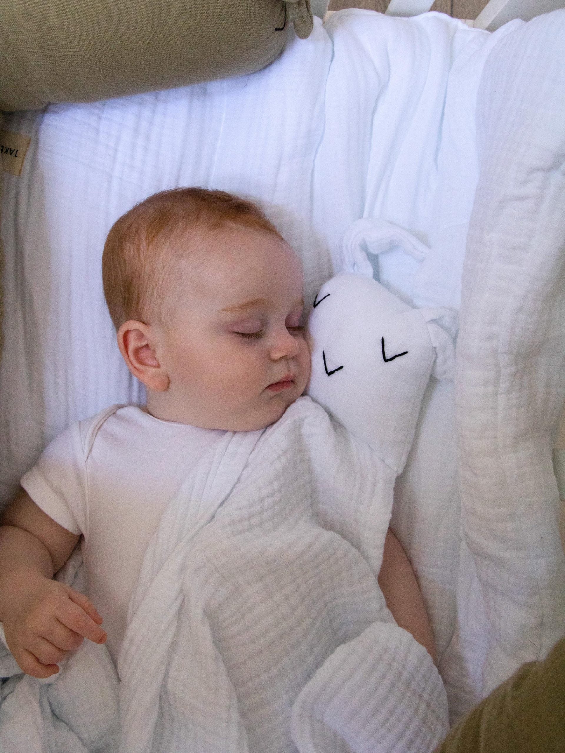תינוק ישן על הספה מכוסה בשמיכת תינוק נבי ארנבי בצבע לבן