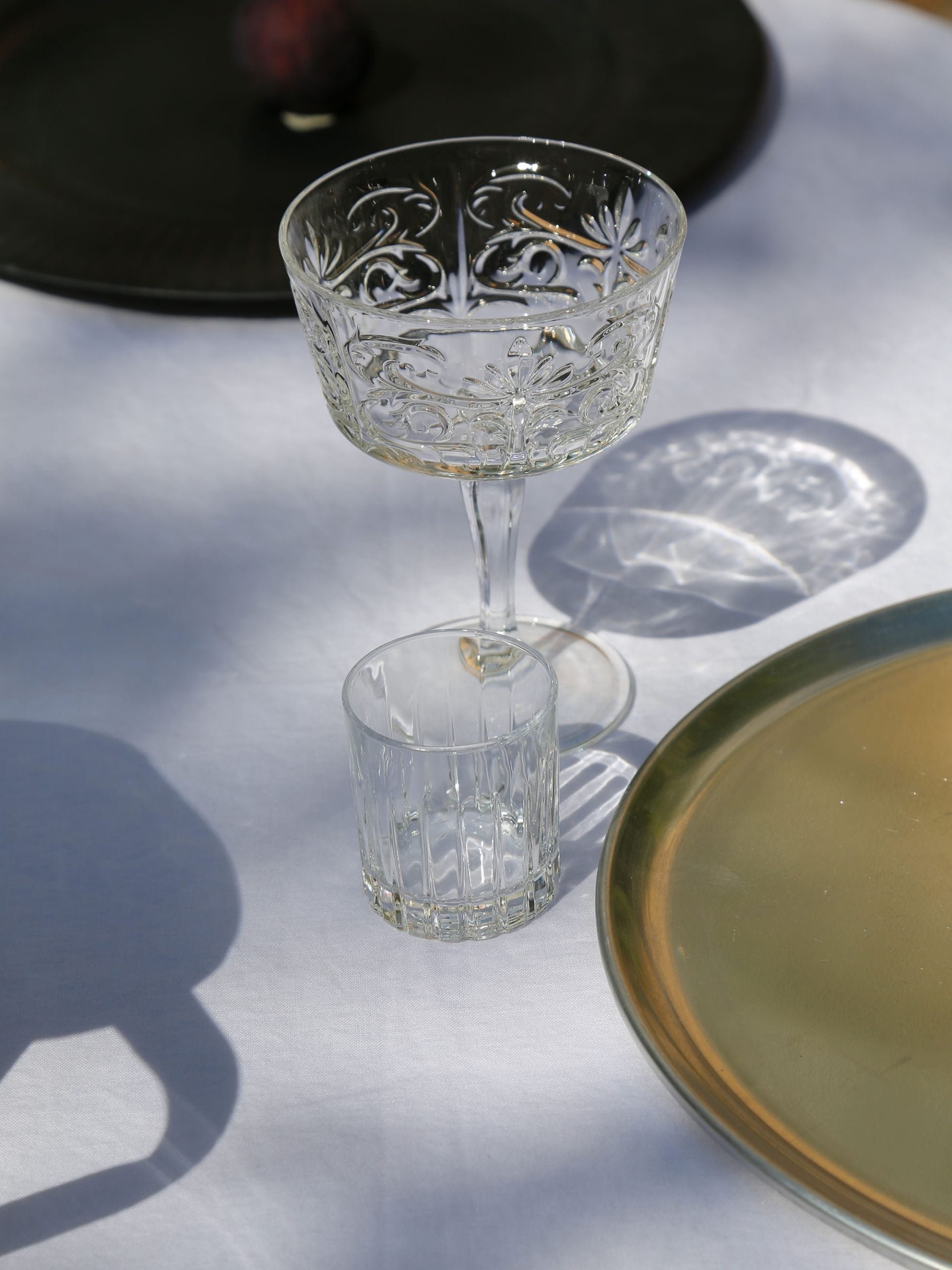 כוס שמפנייה וכוס מים מזכוכית ליד צלחת מעוצבת על שולחן ערוך עם מפה לבנה 
