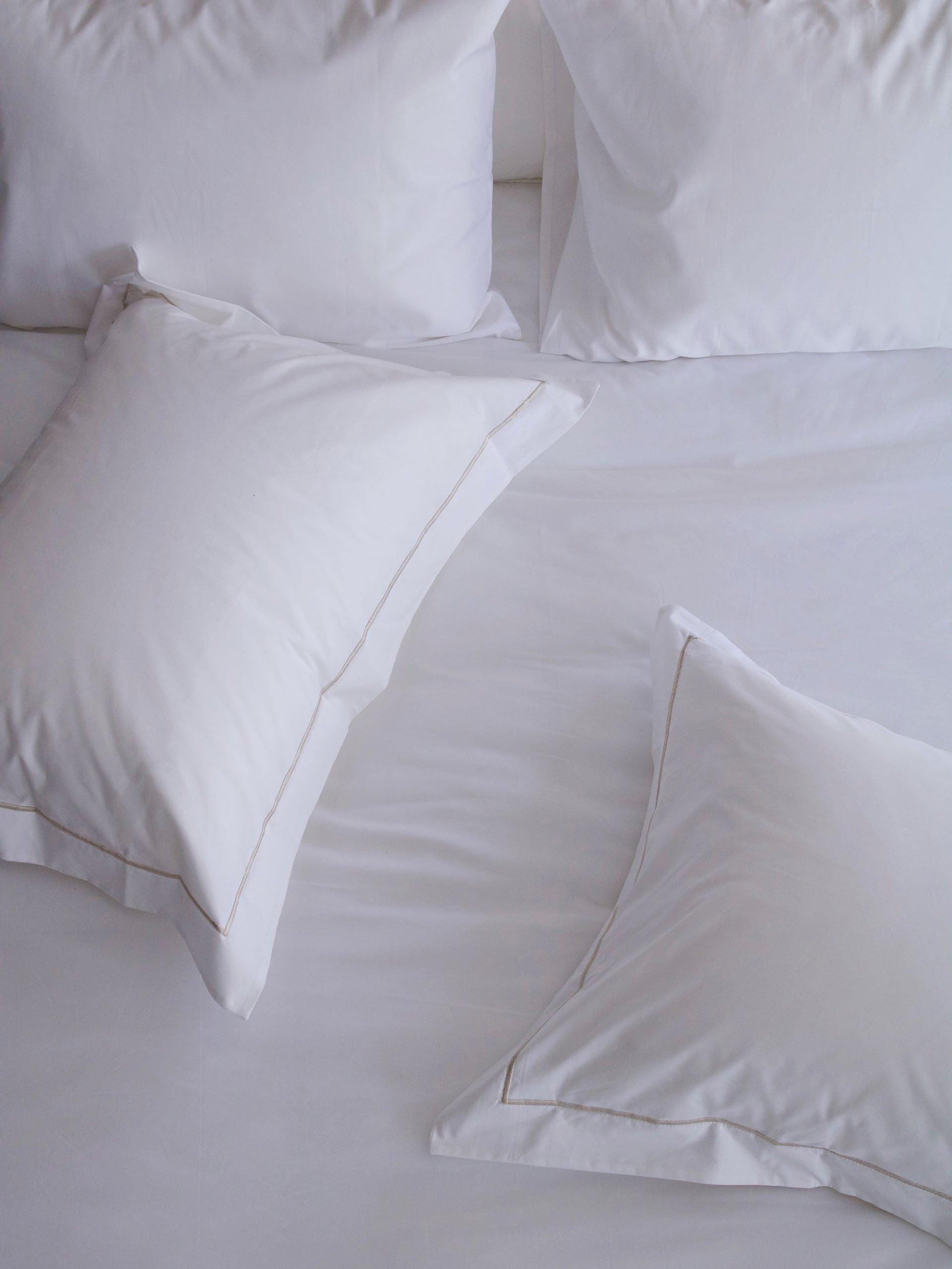 כריות לבנות עם ציפיות לכריות על סדין לבן באור יום