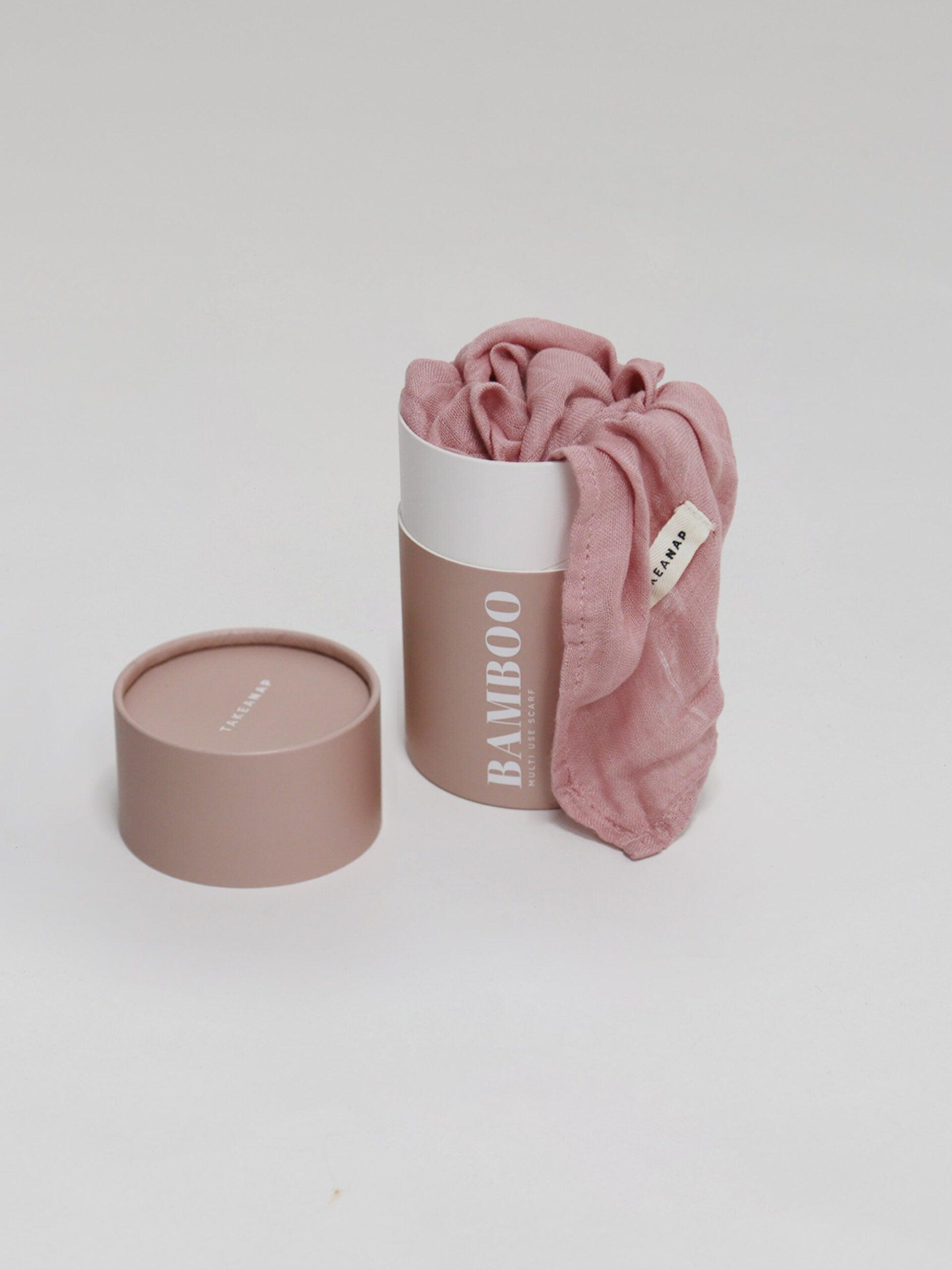 חיתול במבוק בצבע ורוד נשפך מחוץ לאריזה שלו על רקע אפור בהיר בוהק