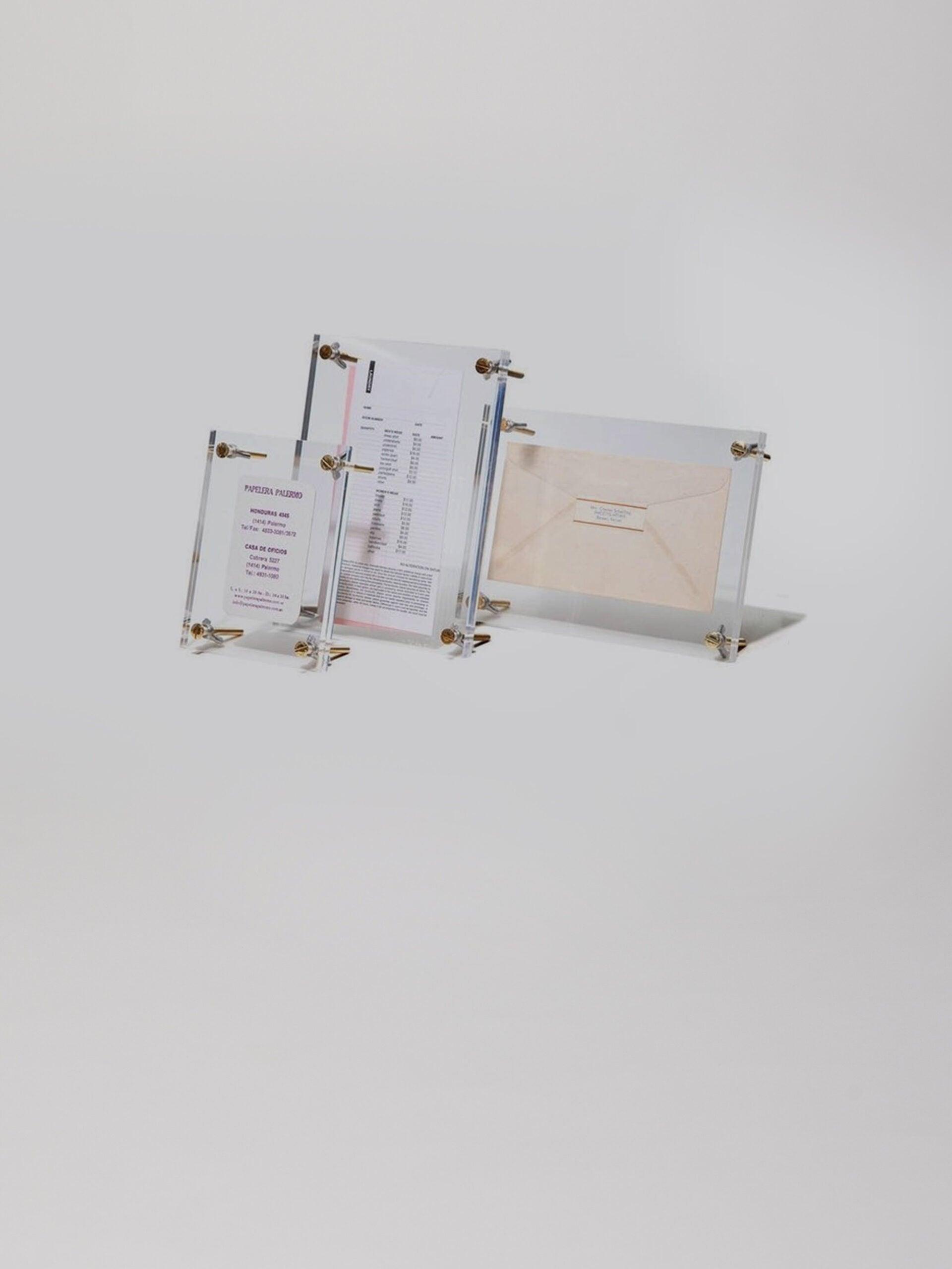 שלושה מסגרות לתמונה מזכוכית אקרילית בגדלים שונים עומדים על רקע אפור בהיר