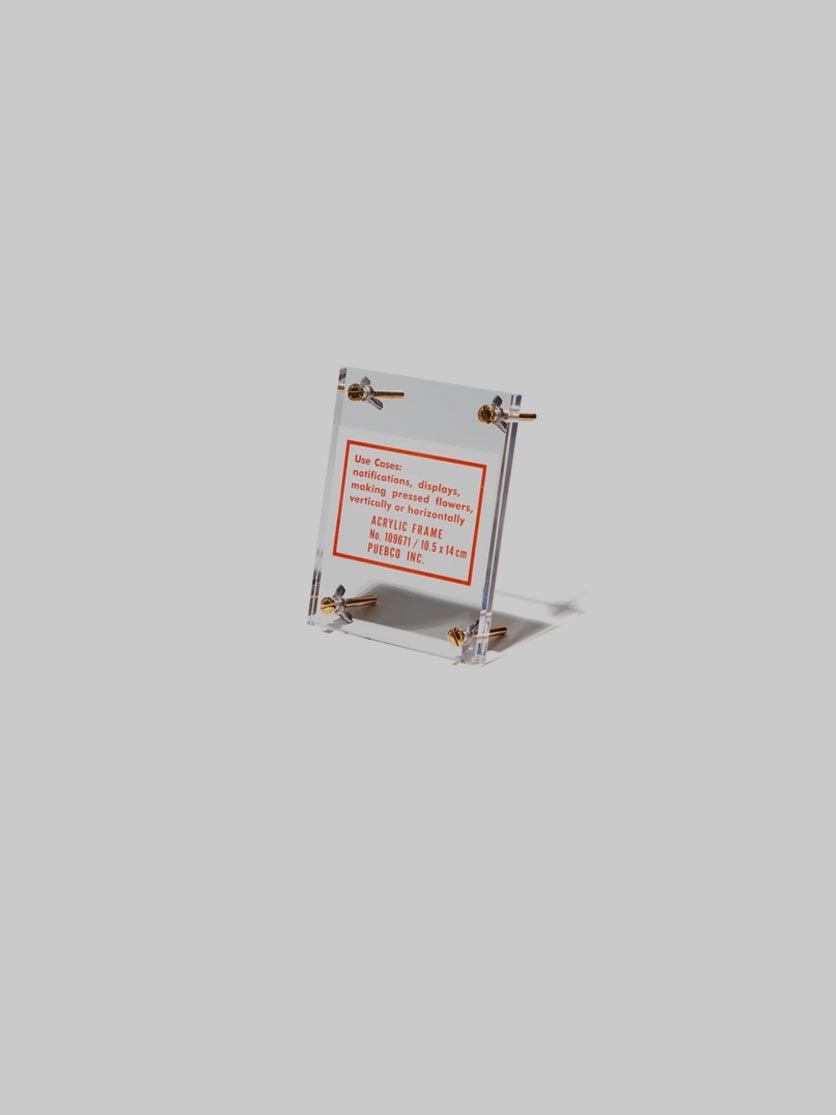 מסגרת לתמונה אקרילית שקופה וקטנה עומדת על רקע אפור בהיר