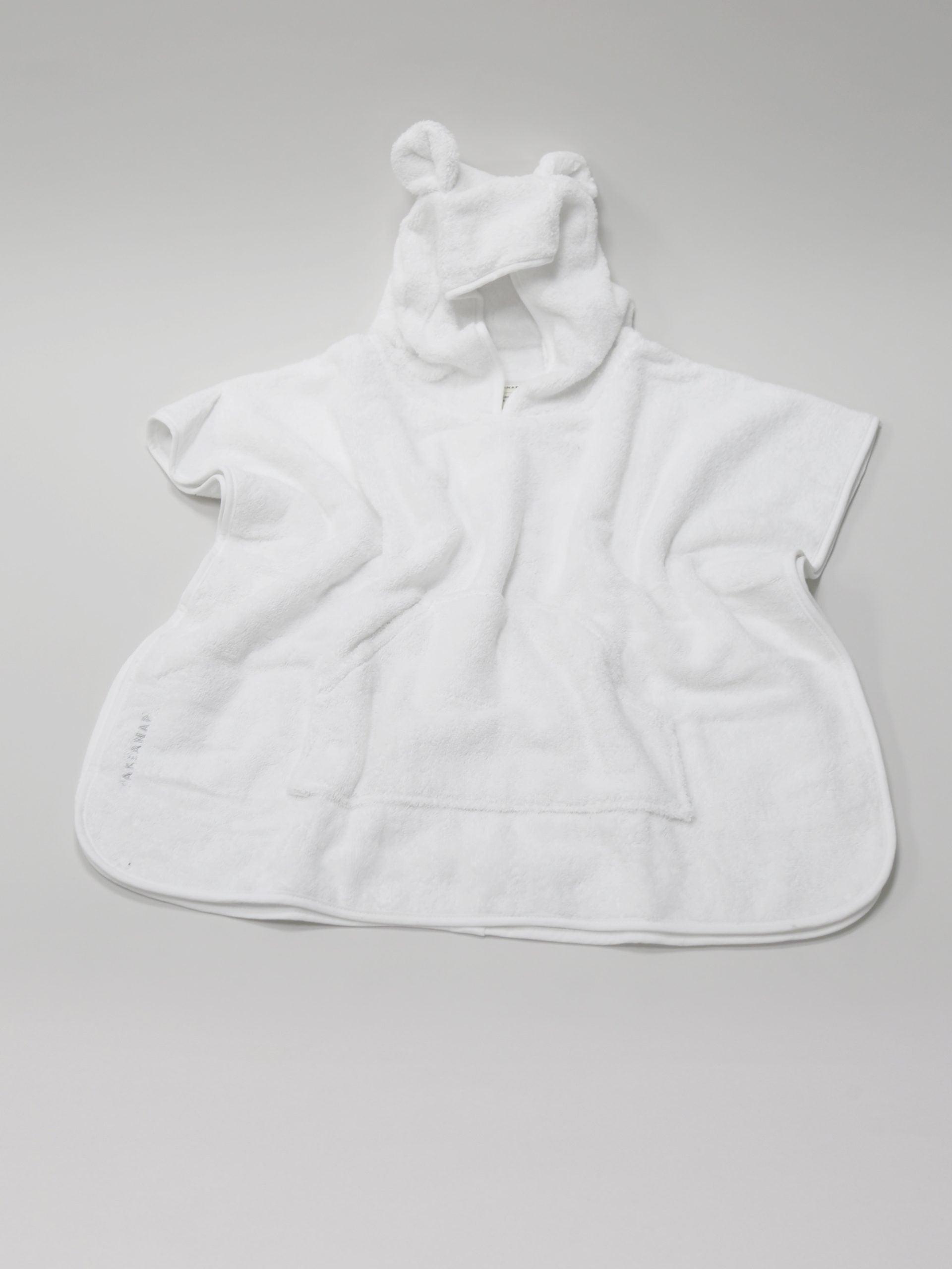מגבת פונצ'ו לילדים בצבע לבן פרושה על רקע אפור
