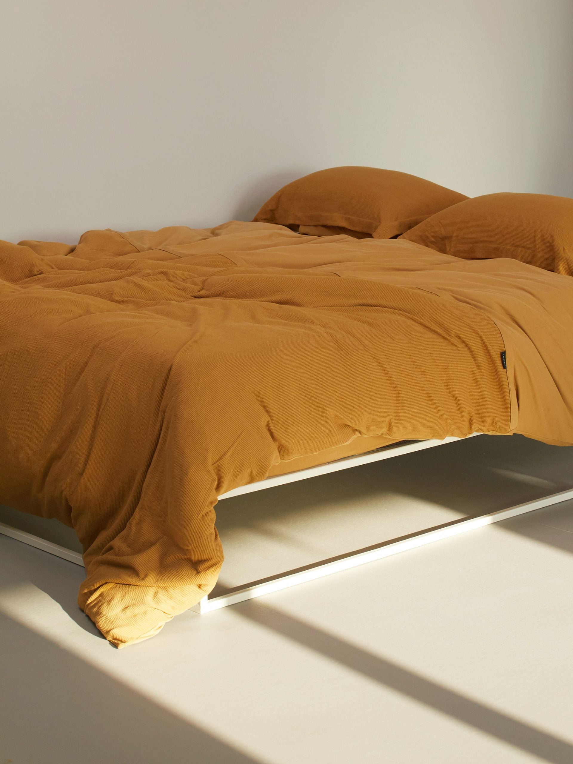 מיטת ברזל לבנה עם מצעים הכוללים סדין, שמיכת פוך עם ציפה לשמיכה כרית וציפית לכרית בצבע קרמל