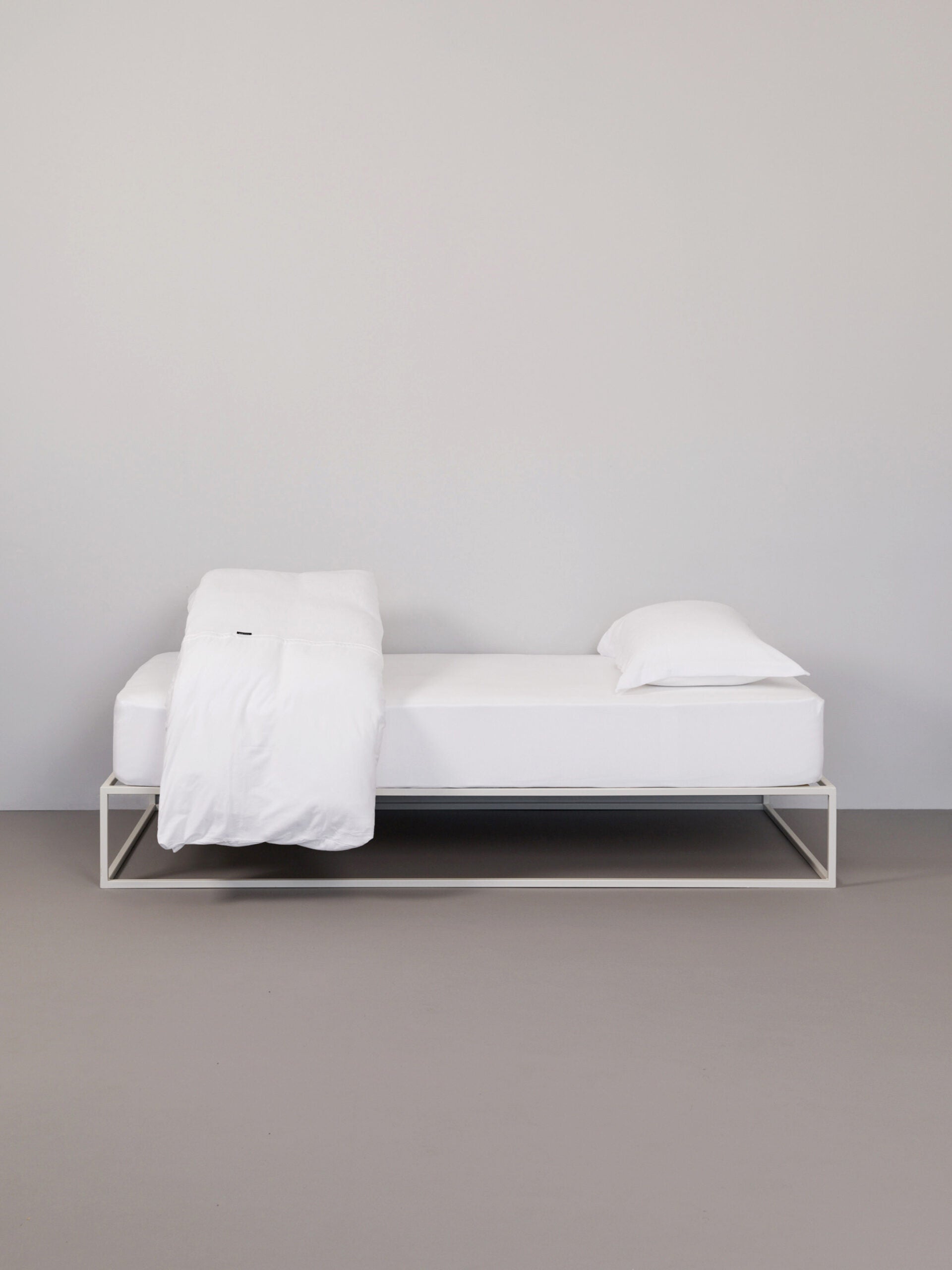 בתמונה: מיטת ברזל לבנה עם סדין, שמיכת פוך וכרית עם ציפית לכרית טריקו Jacquard בצבע לבן