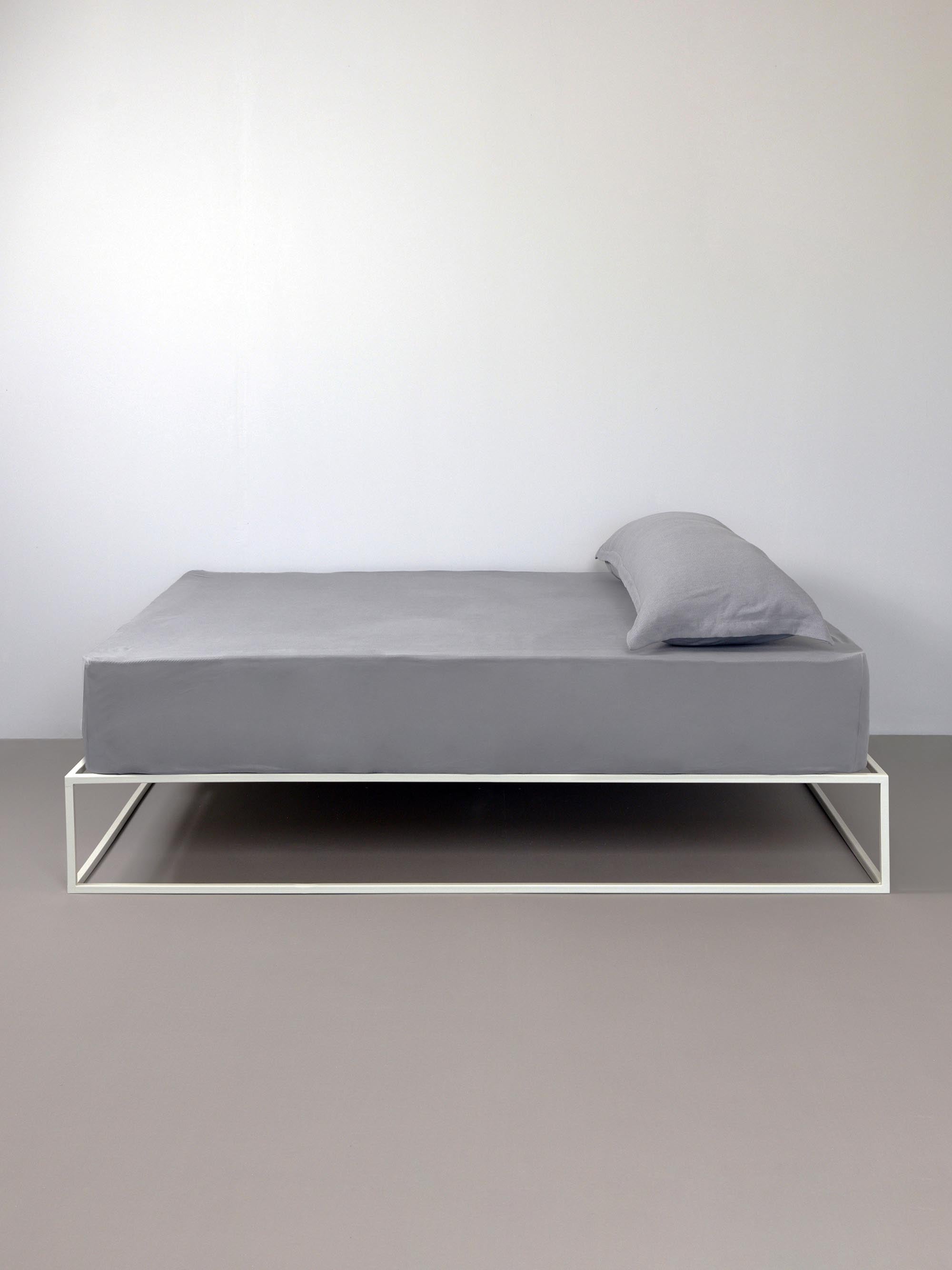 מיטת ברזל לבנה עם סדין, כרית וציפית לכרית ארוכה בצבע  אפור
