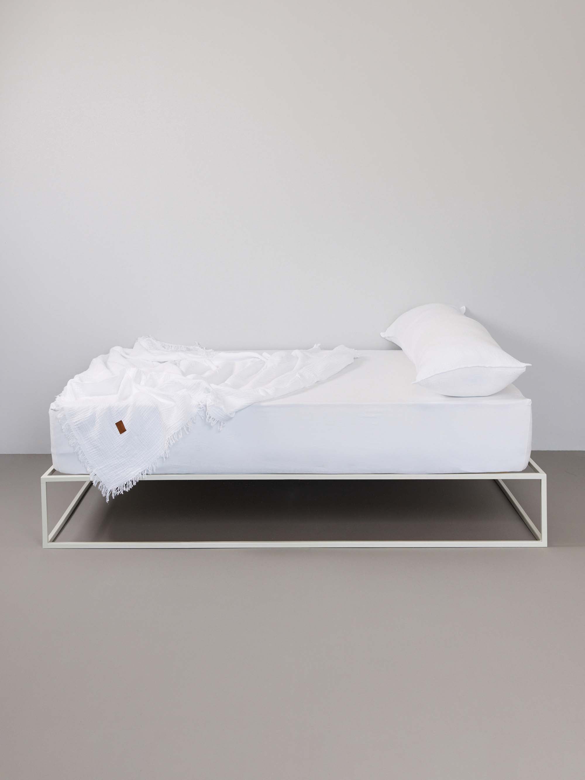 מיטת ברזל לבנה עם סדין, כרית וציפית לכרית ארוכה בצבע לבן