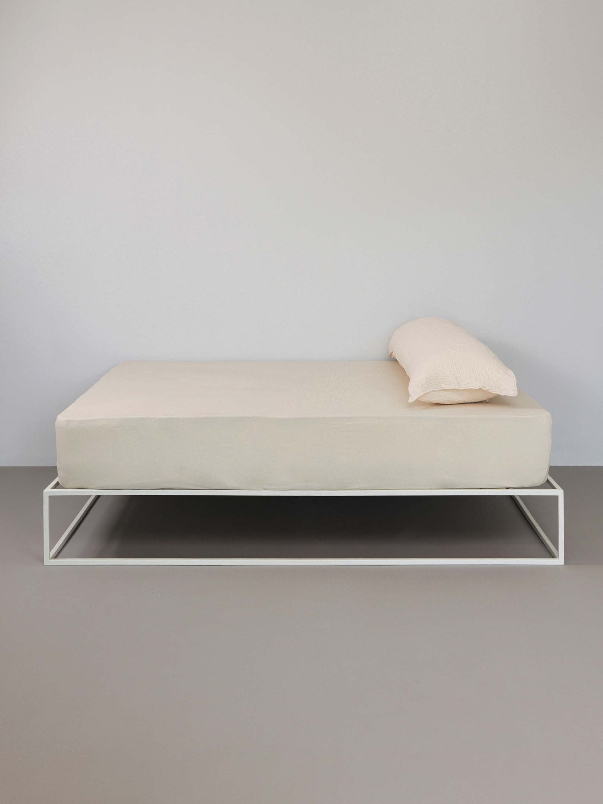 מיטת ברזל לבנה עם סדין, כרית וציפית לכרית ארוכה בצבע אבן