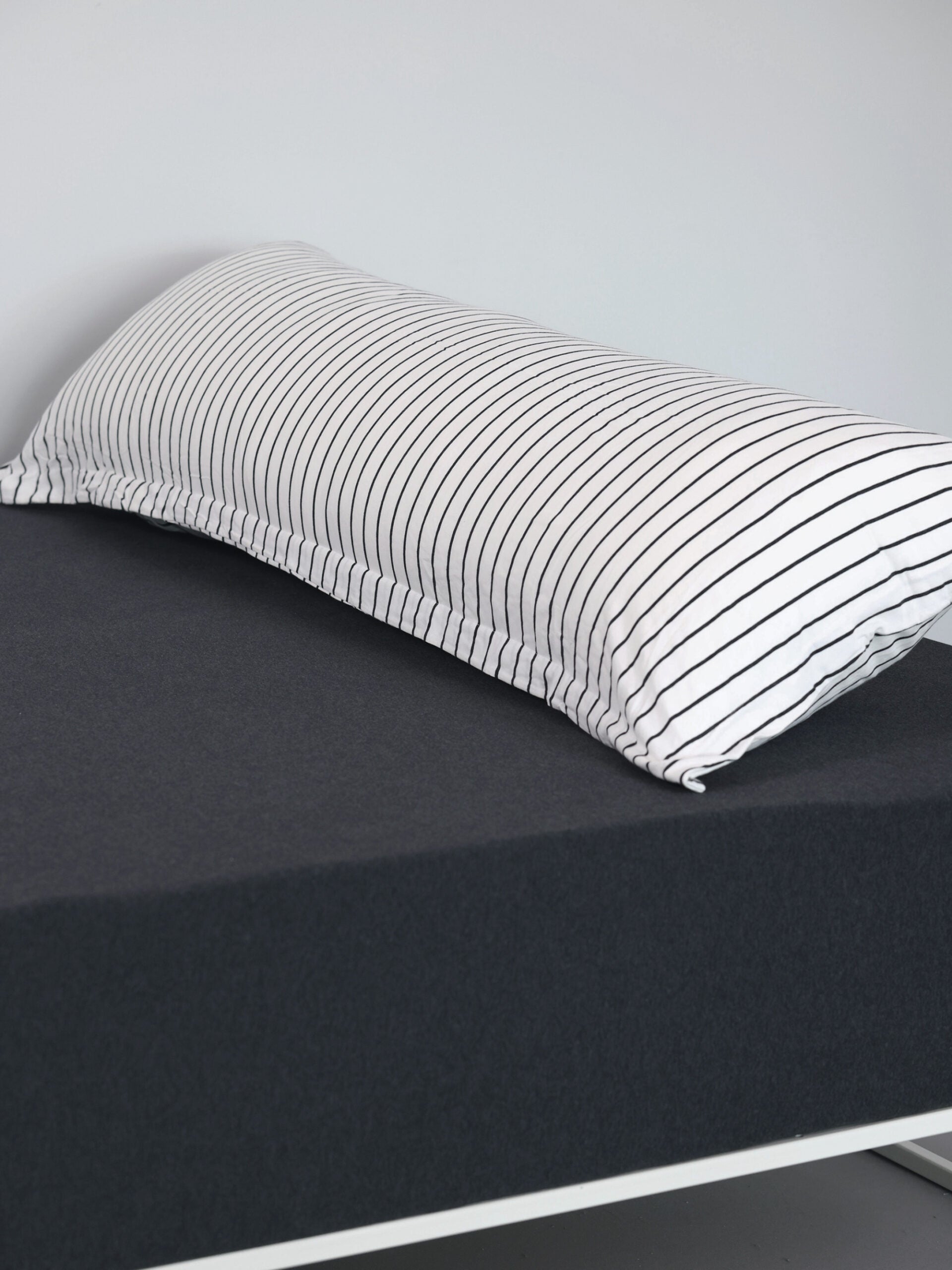 ראש מיטת ברזל לבנה עם סדין, כרית ארוכה וציפית לכרית Stripes בחדר אפור