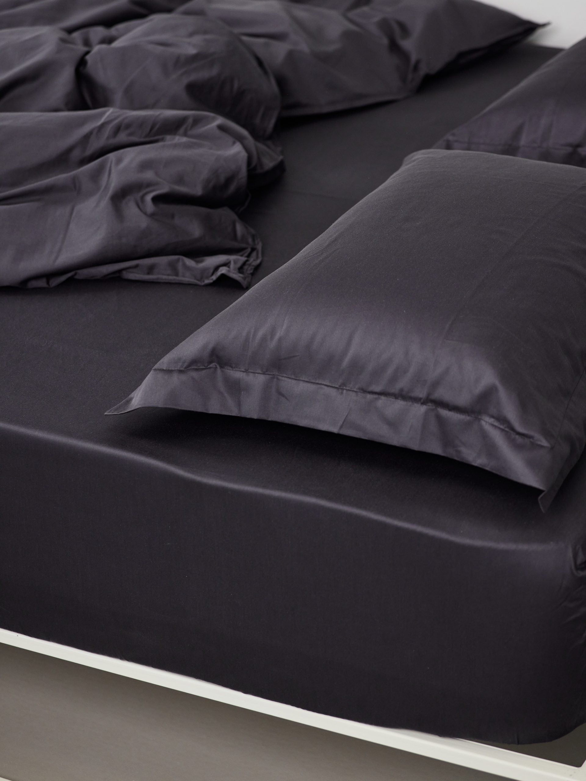 מיטת ברזל לבנה עם סדין, שמיכת פוך, כריות וציפיות לכריות בצבע פחם