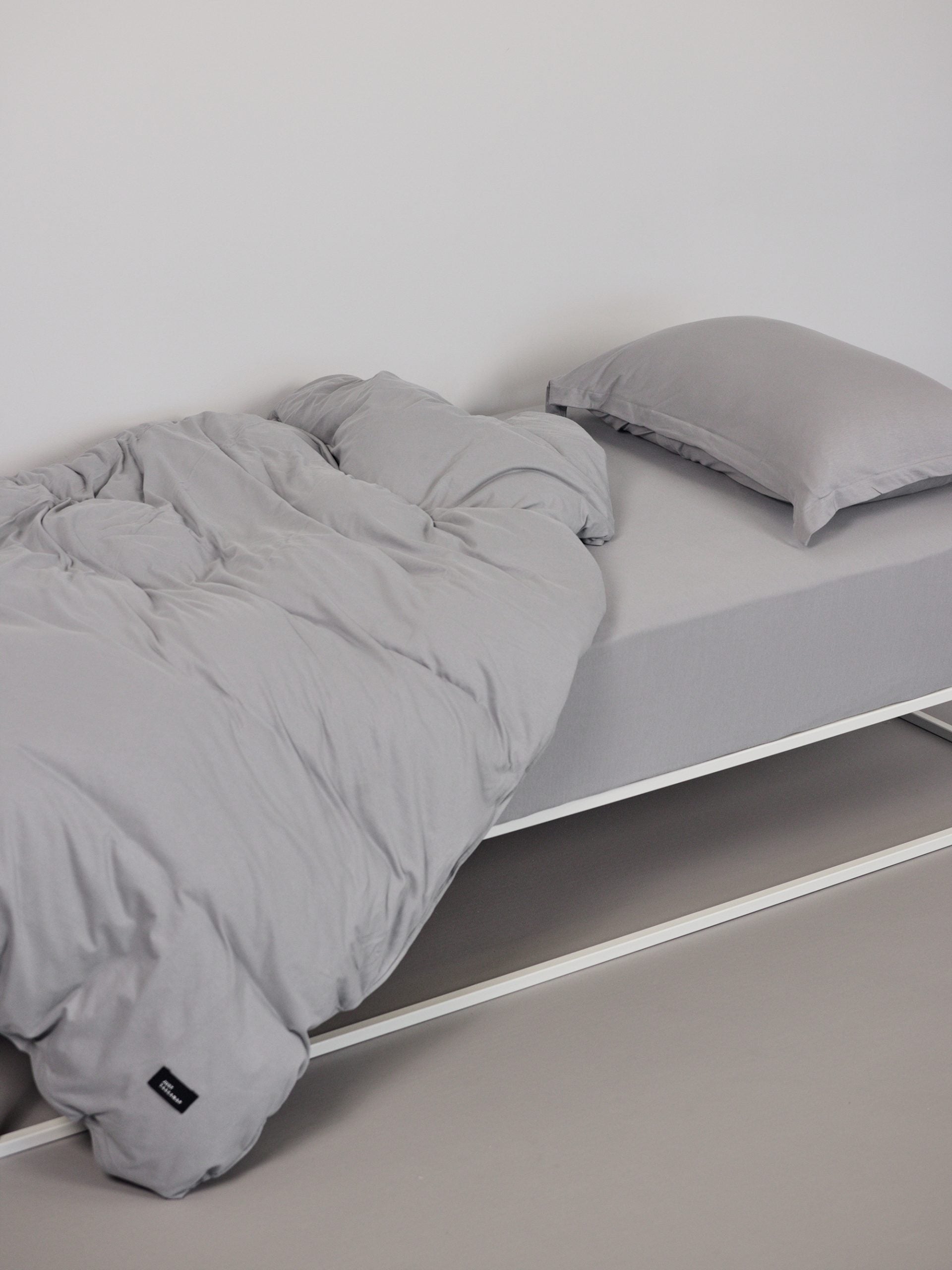 מיטת ברזל לבנה עם סט מצעים וכריות עם ציפיות לכריות בצבע אפור