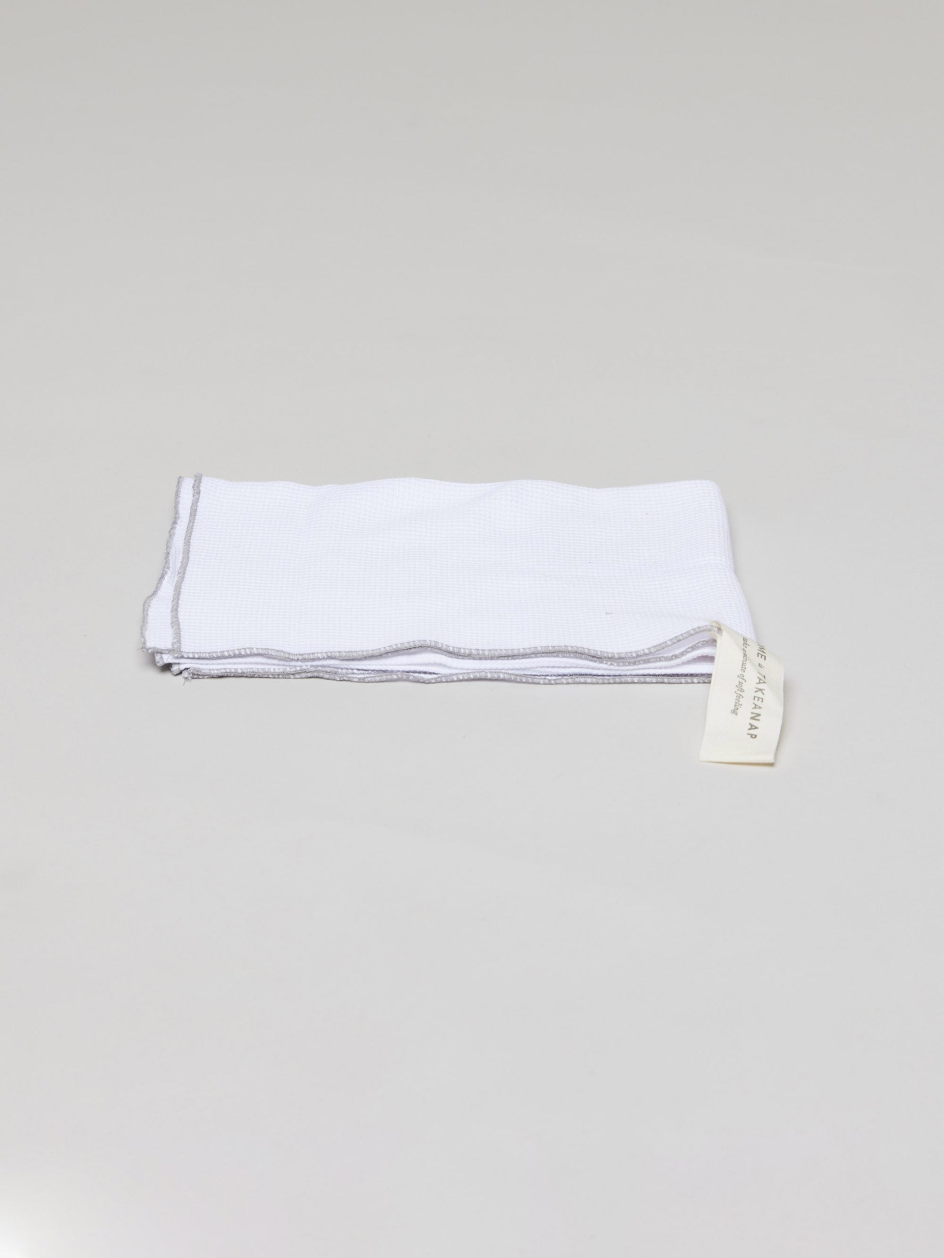 מגבת מטבח ג'קארד בצבע לבן על רקע אפור בהיר