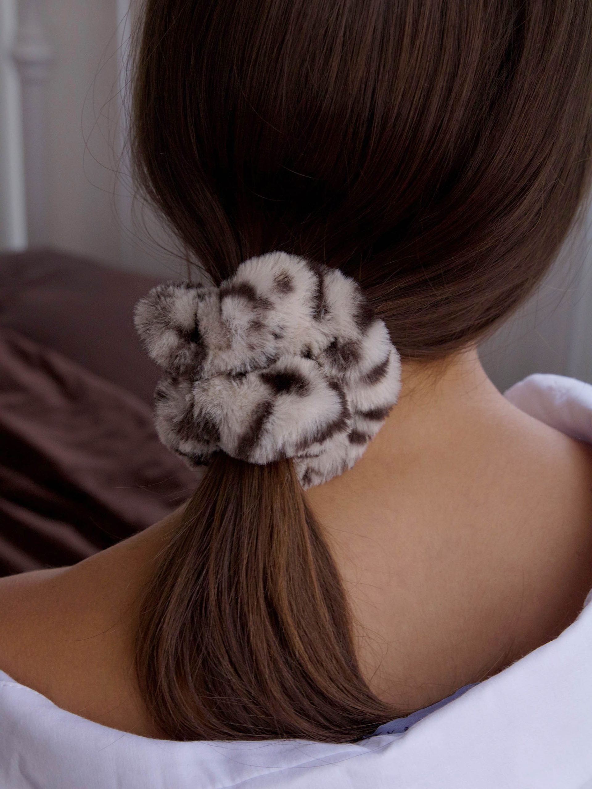 גב אישה עם גומיית סקראנצ'י בצבע מנומר על שערה