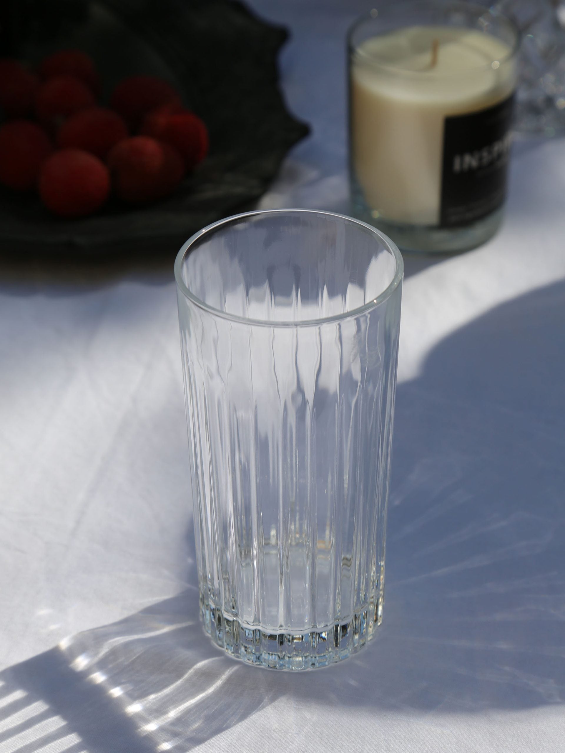 כוס הייבול טיימלאס מזכוכית קריסטל על שולחן עם מפה לבנה ונר ריחני בצבע לבן