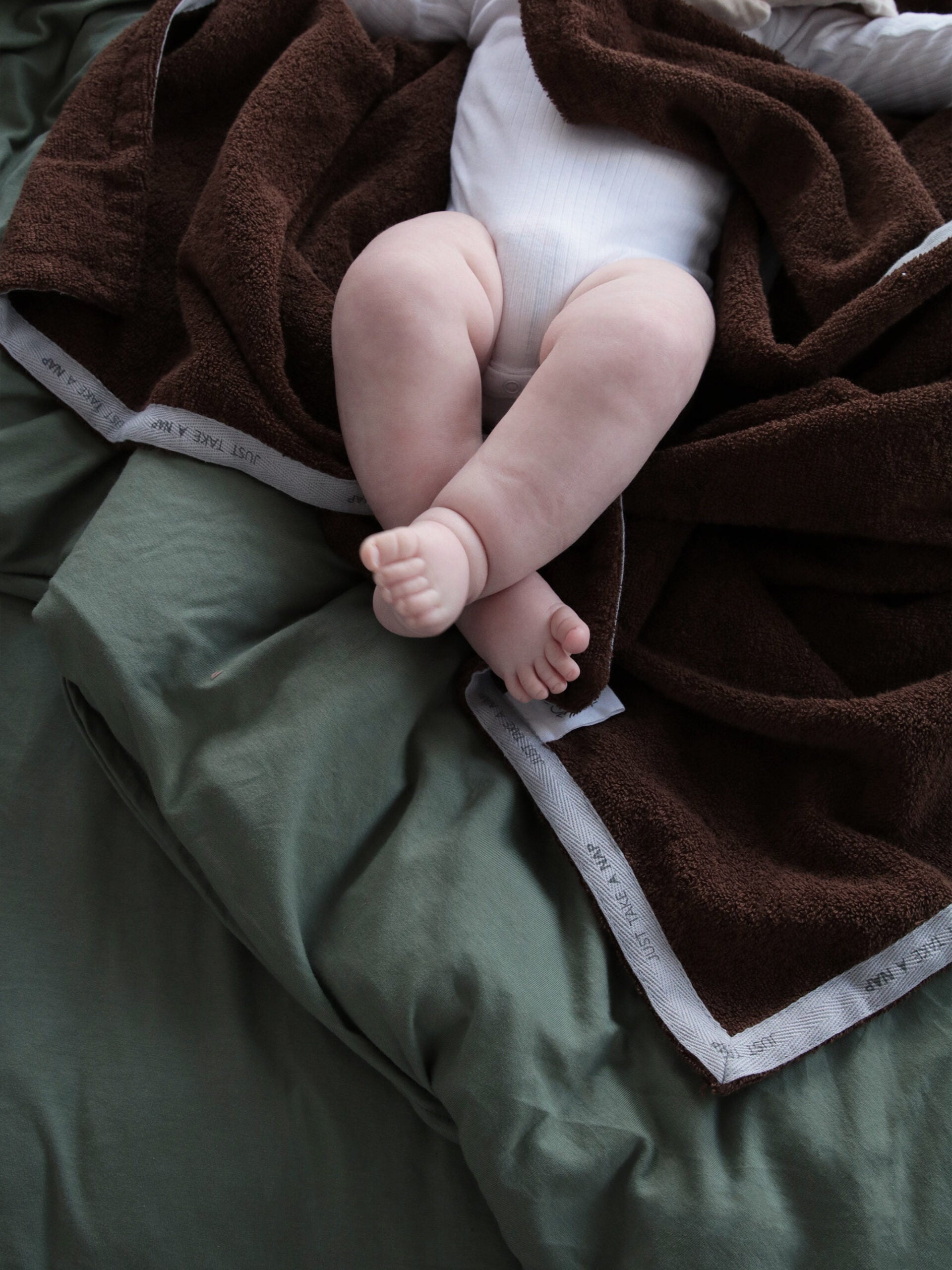 תינוק על מיטה עם מצעים מכוסה במגבת חיבוקי לתינוק  