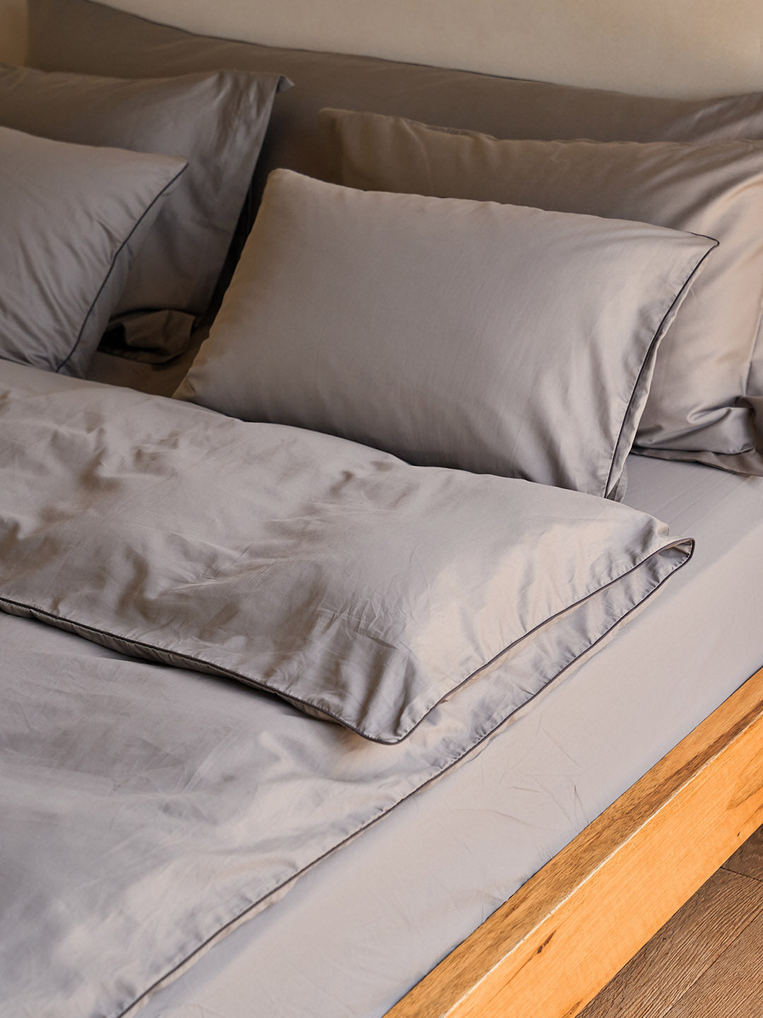 כריות ארוכות בצבע אפור מסדרת נייס על מיטה עם מצעים 