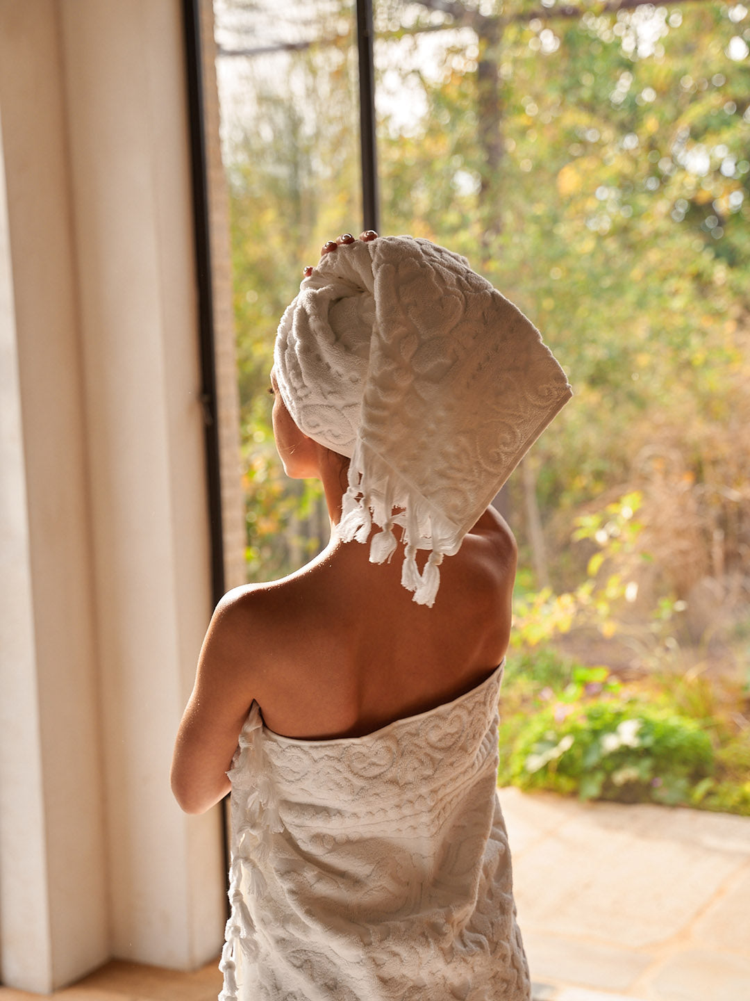 אישה חובשת מגבת על הראש ומגבת גוף 