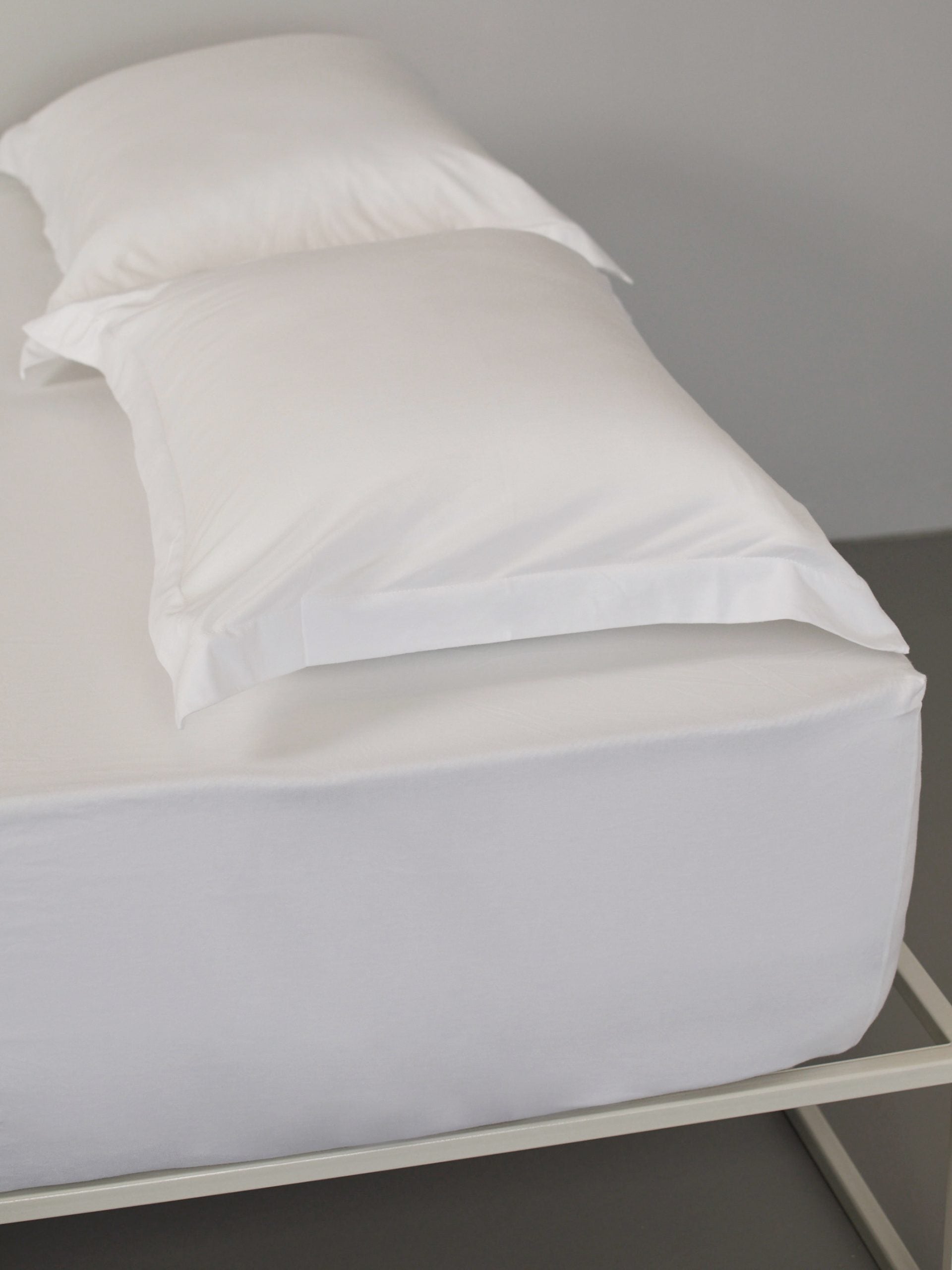 ראש מיטת ברזל לבנה עם סט מצעים וכריות עם ציפיות לכריות בצבע לבן