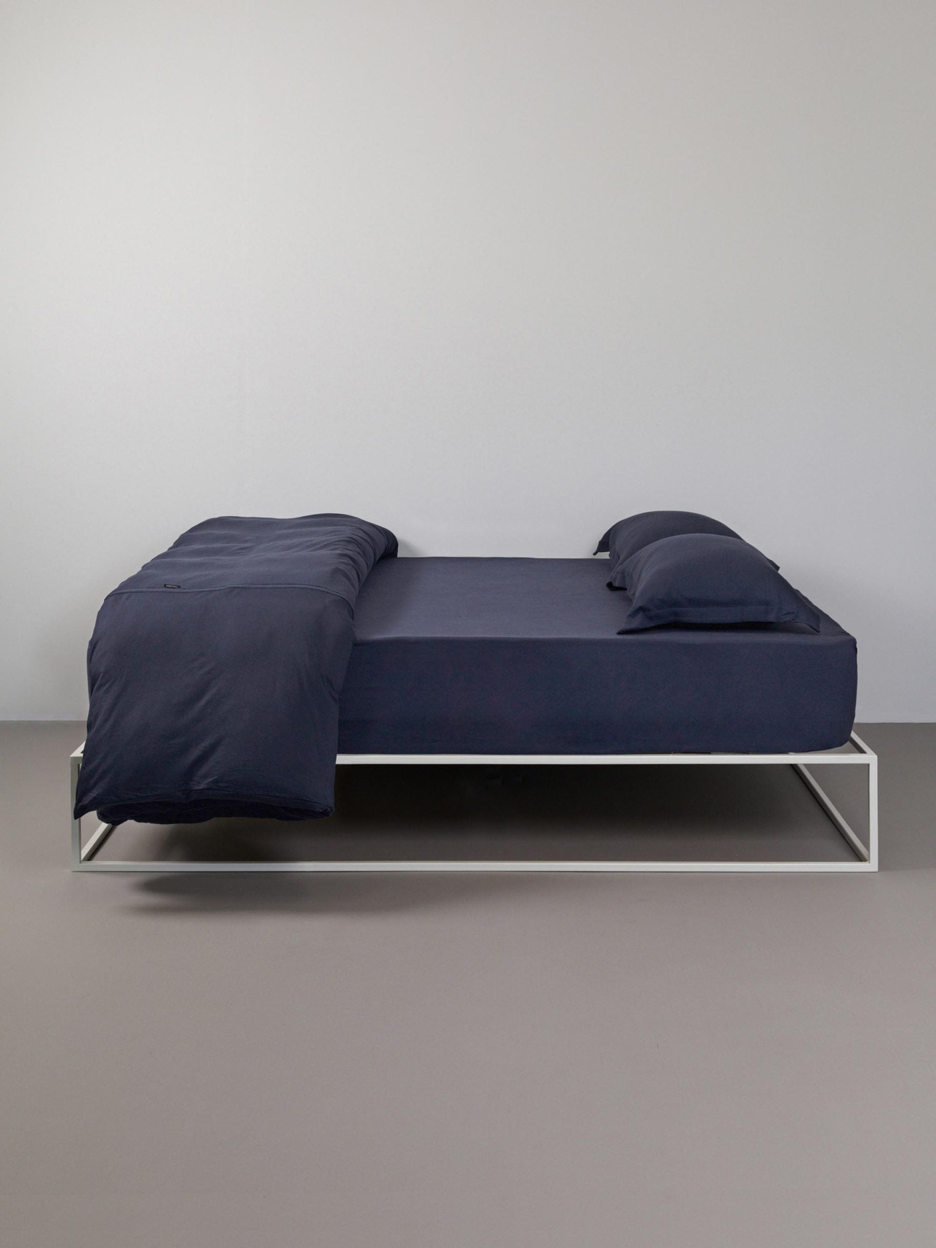מיטת ברזל לבנה עם מצעים הכוללים סדין, שמיכת פוך עם ציפה לשמיכה כרית וציפית לכרית בצבע כחול